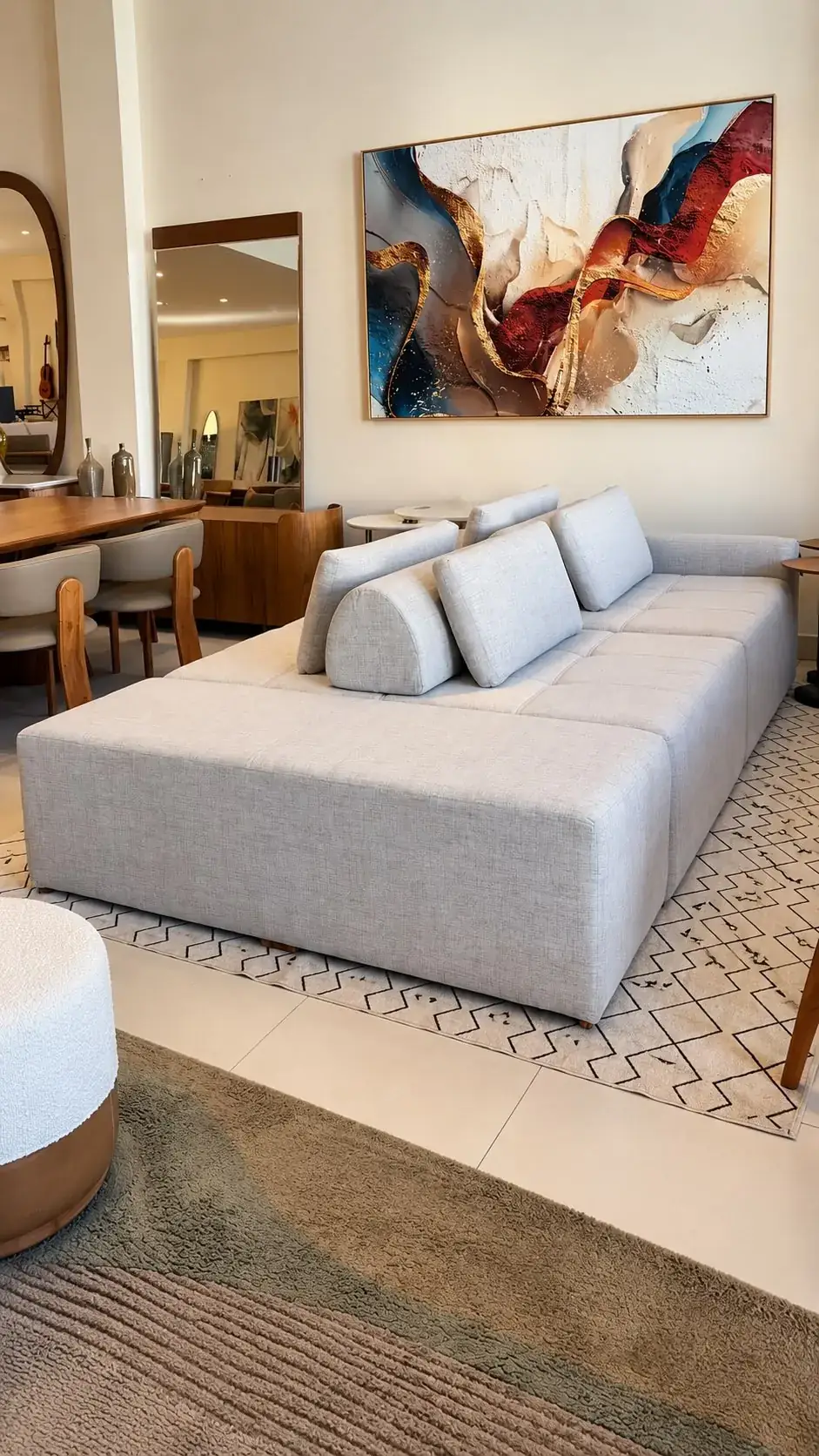 Sofá ilha em tecido claro com almofadas generosas no showroom da Cumaru